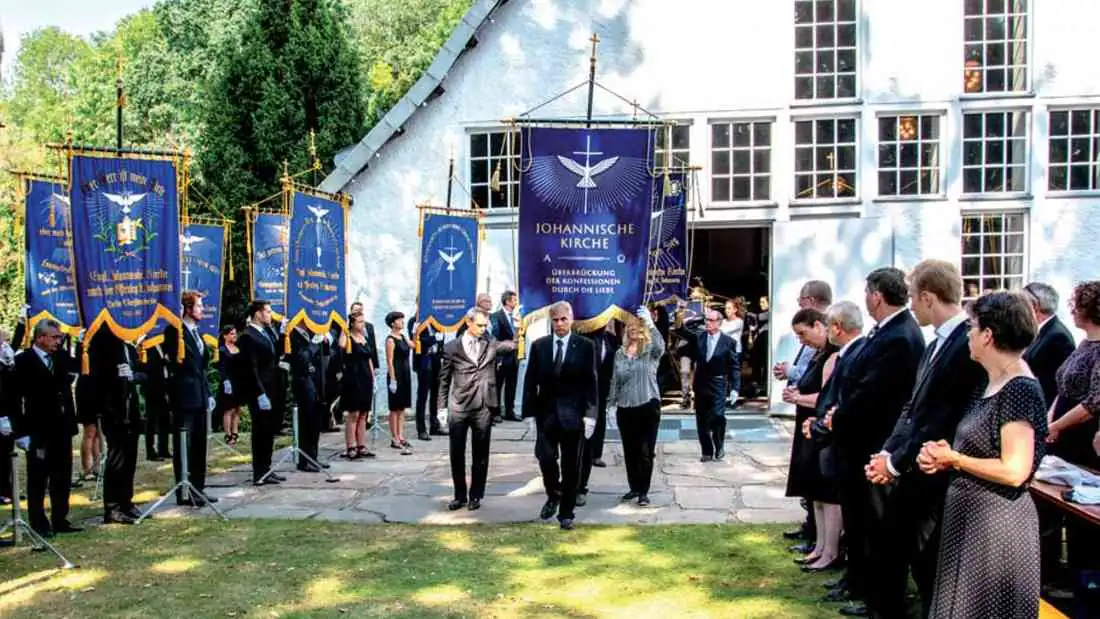 Prozession mit Gemeindefahnen vor der Kirche im Waldfrieden
